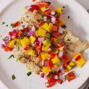 Overhead view of a plate of halibut with mango salsa on top.