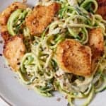 Pinterest graphic of a plate of chicken Alfredo with zucchini noodles with red chili flakes on top.