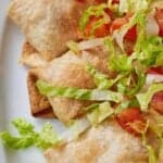 Pinterest graphic of a close view of three chicken chimichanga with shredded lettuce and tomatoes on top.