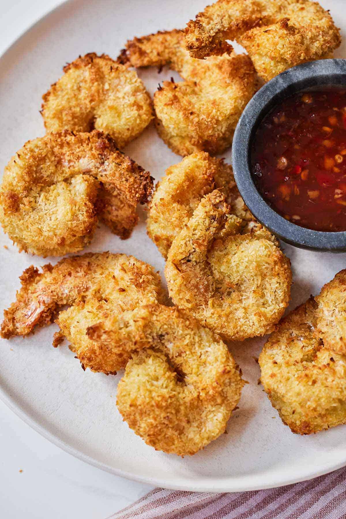 A plate of air fryer coconut shrimp with a dip on the side.