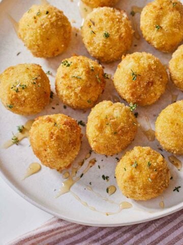 A plate of air fryer goat cheese balls with honey drizzled on top.