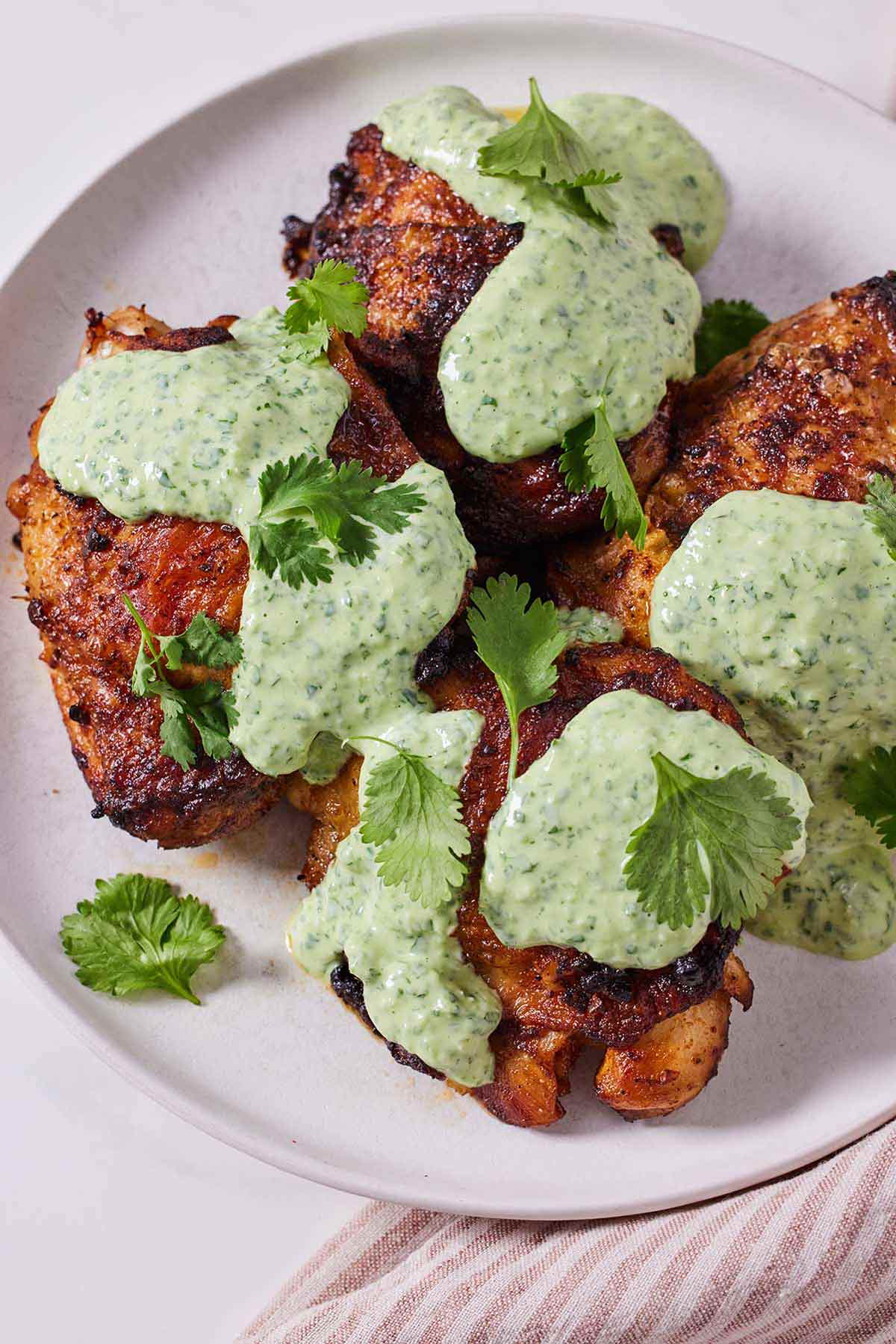 A plate of air fryer Peruvian chicken with sauce drizzled over top with fresh cilantro.