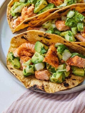 Overhead view of a plate of three salmon tacos.