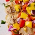 Pinterest graphic of a close view of freshly grilled halibut with mango salsa on top.
