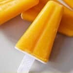 Pinterest graphic of a mango popsicle leaned up against more popsicles.