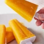 Pinterest graphic of a mango popsicle held up.