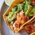 Pinterest graphic of a close up view of a salmon taco with two lime wedges beside it.