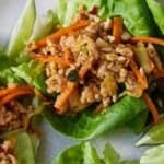 Pinterest graphic of a close up view of one Thai chicken lettuce wrap on a plate.
