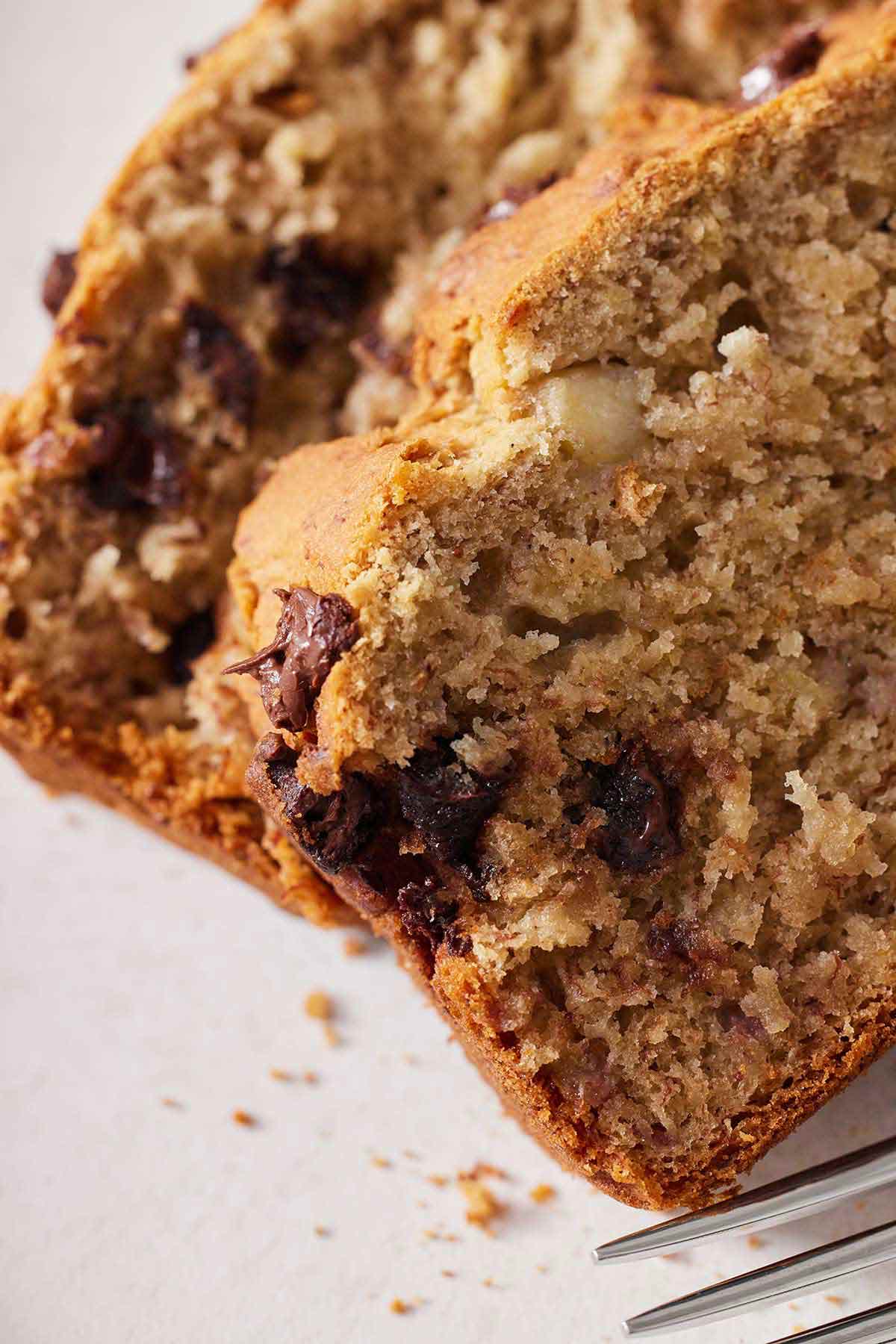 Close up view of two slices of gluten free chocolate chip banana bread, highlighting the moist and tender crumb.