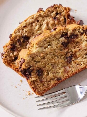 A plate with two slices of gluten free chocolate chip banana bread with a fork beside them.