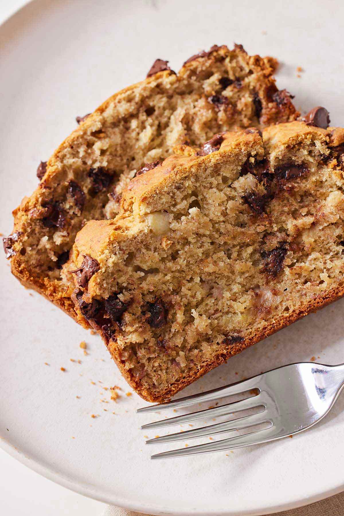 A plate with two slices of gluten free chocolate chip banana bread with a fork beside them.