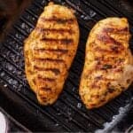Pinterest graphic of two Mediterranean grilled chicken breasts on a grill pan.
