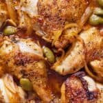 Pinterest graphic of a close view of saucy braised chicken with olives and onions tucked around them.