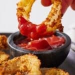 Pinterest graphic of an air fryer onion ring dipped into ketchup.