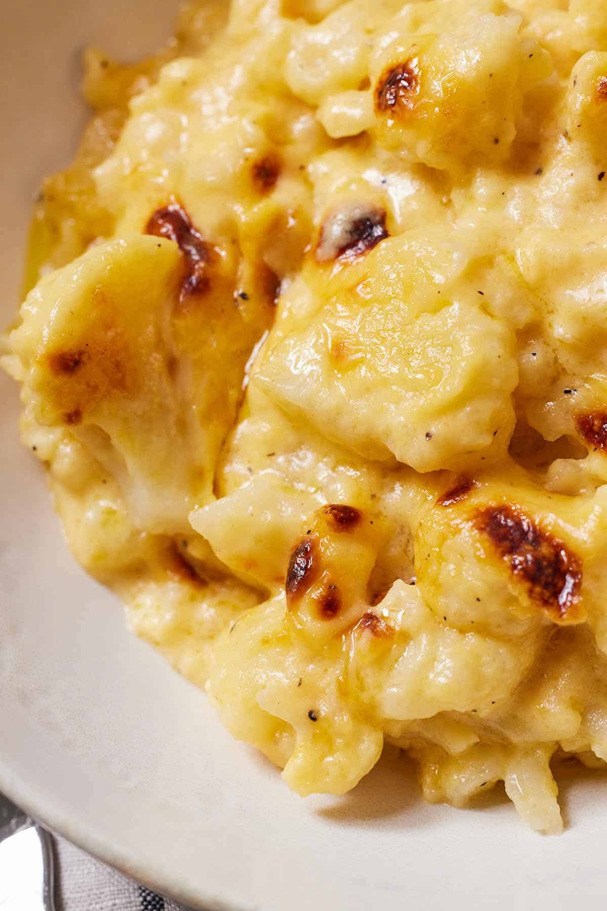 Close up view of cauliflower mac and cheese with some golden bits of cheese.