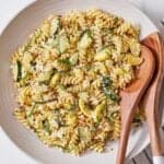 Overhead view of a plate of summer squash pasta with two wooden serving spoons on the side.