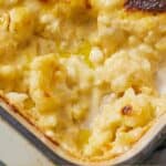 Pinterest graphic of a close view of the corner of a baking dish of cauliflower mac and cheese with a portion scooped out.