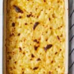 Pinterest graphic of an overhead view of a baking dish with cauliflower mac and cheese with golden cheese on top.