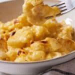 Pinterest graphic of a forkful of cauliflower mac and cheese lifted from a bowl.
