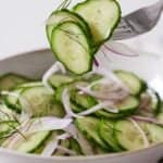 Pinterest graphic of a forkful of cucumber salad lifted from the bowl underneath.