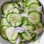 Pinterest graphic of an overhead view of a bowl of cucumber salad with fresh dill sprinkled on top.