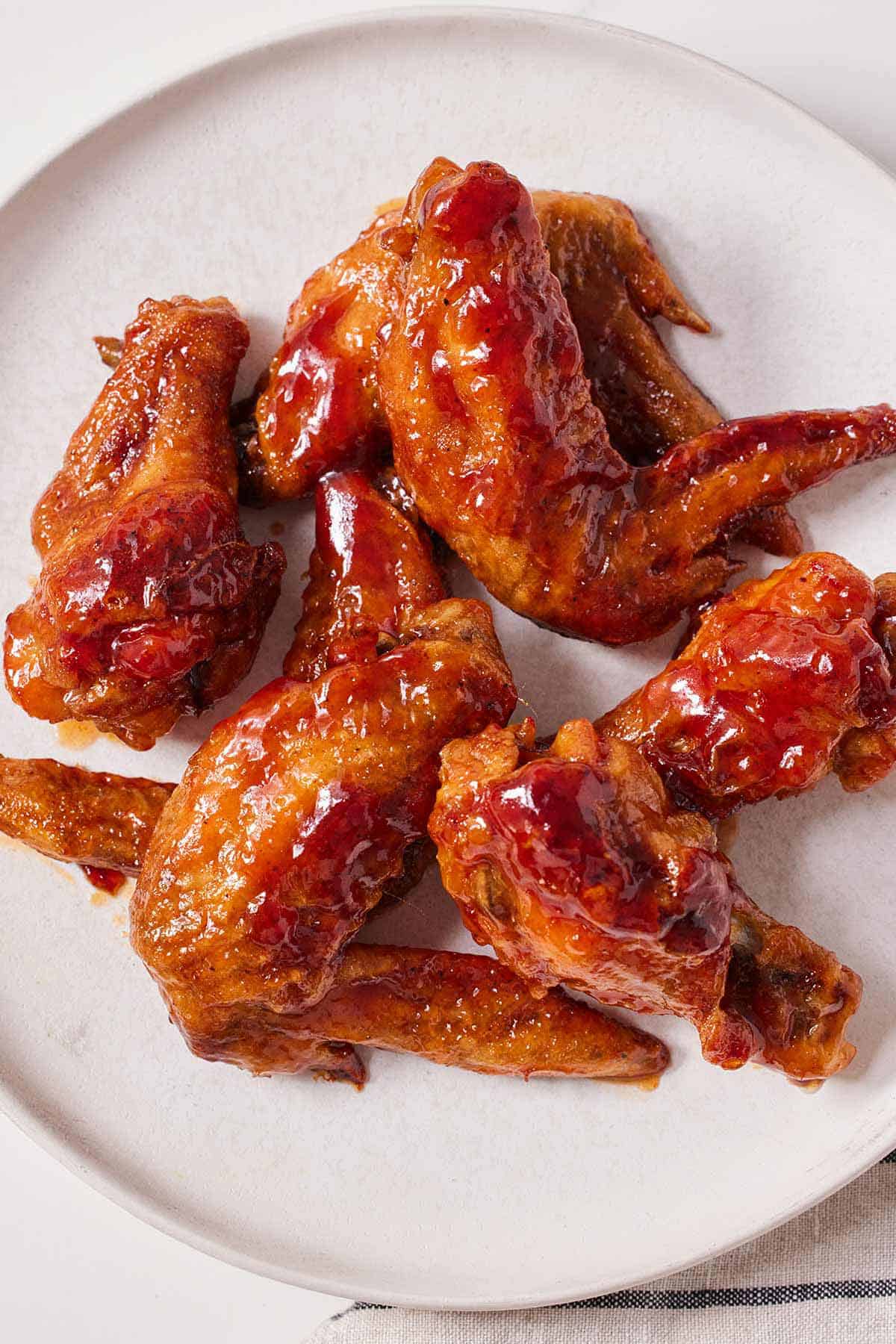 A plate with multiple honey BBQ wings on a white plate.