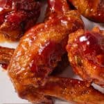 Pinterest graphic of a close view of a chicken wing with honey BBQ sauce.