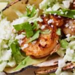 Pinterest graphic of a close up view of the shrimp in a shrimp tacos with chopped cilantro and cotija sprinkled over top.