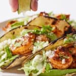 Pinterest graphic of a lime being squeezed over shrimp tacos.