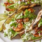 Pinterest graphic of three shrimp tacos on a plate with cotija cheese crumbled on top.