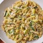 Pinterest graphic of a plate of summer squash pasta with basil, red chili flakes, and goat cheese sprinkled on top.