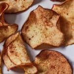 Pinterest graphic of a close up view of air fryer apple chips with cinnamon on them.