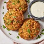Pinterest graphic of a plate of three air fryer crab cakes with a dip on the side.
