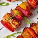 Pinterest graphic of a close view of a Hawaiian chicken skewer with some green onion garnish.