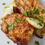 Pinterest graphic of two pieces of air fryer Lebanese chicken with lemon slices and chopped parsley.