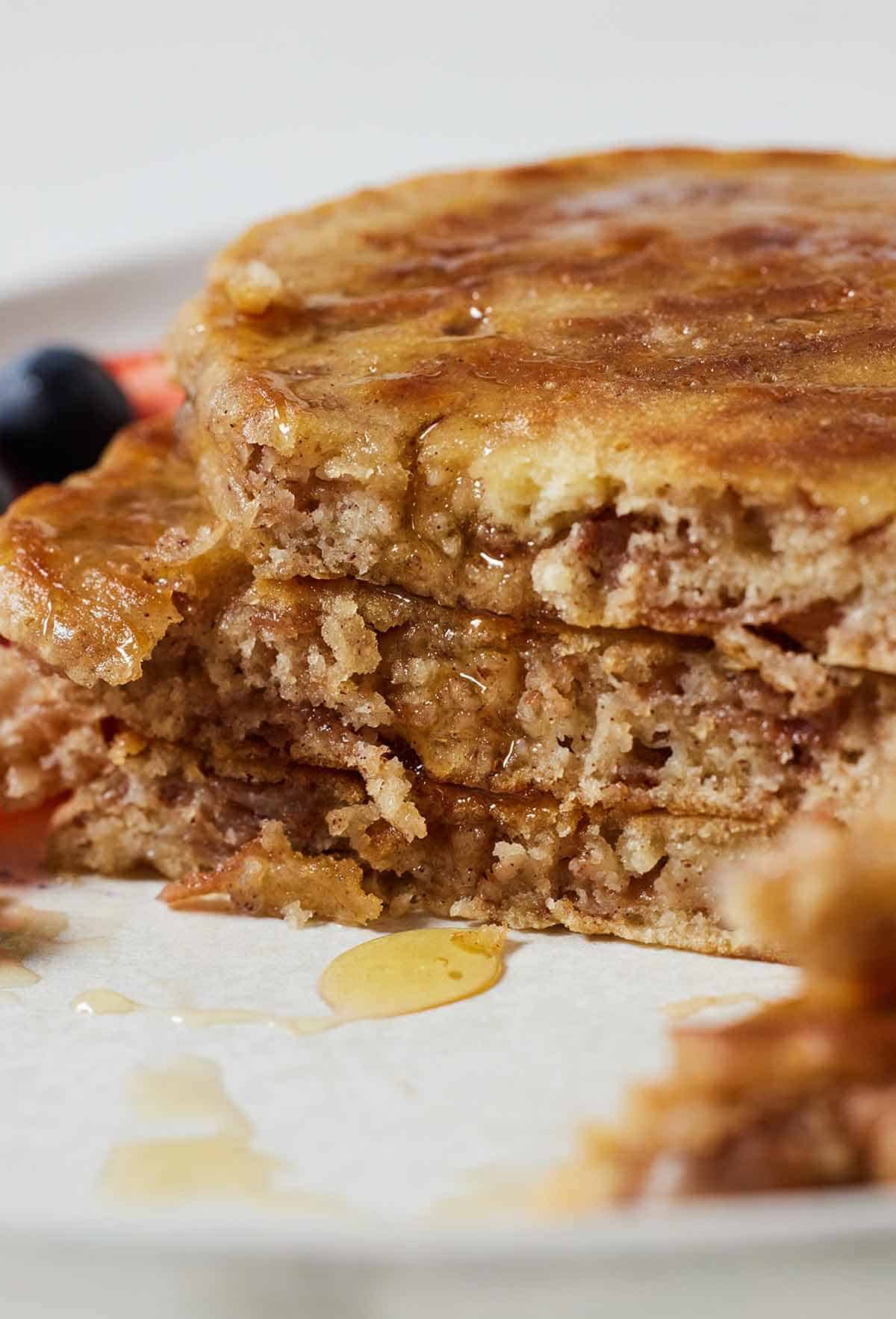 Close view of three apple pancakes stacked with a portion cut, showing the inside.