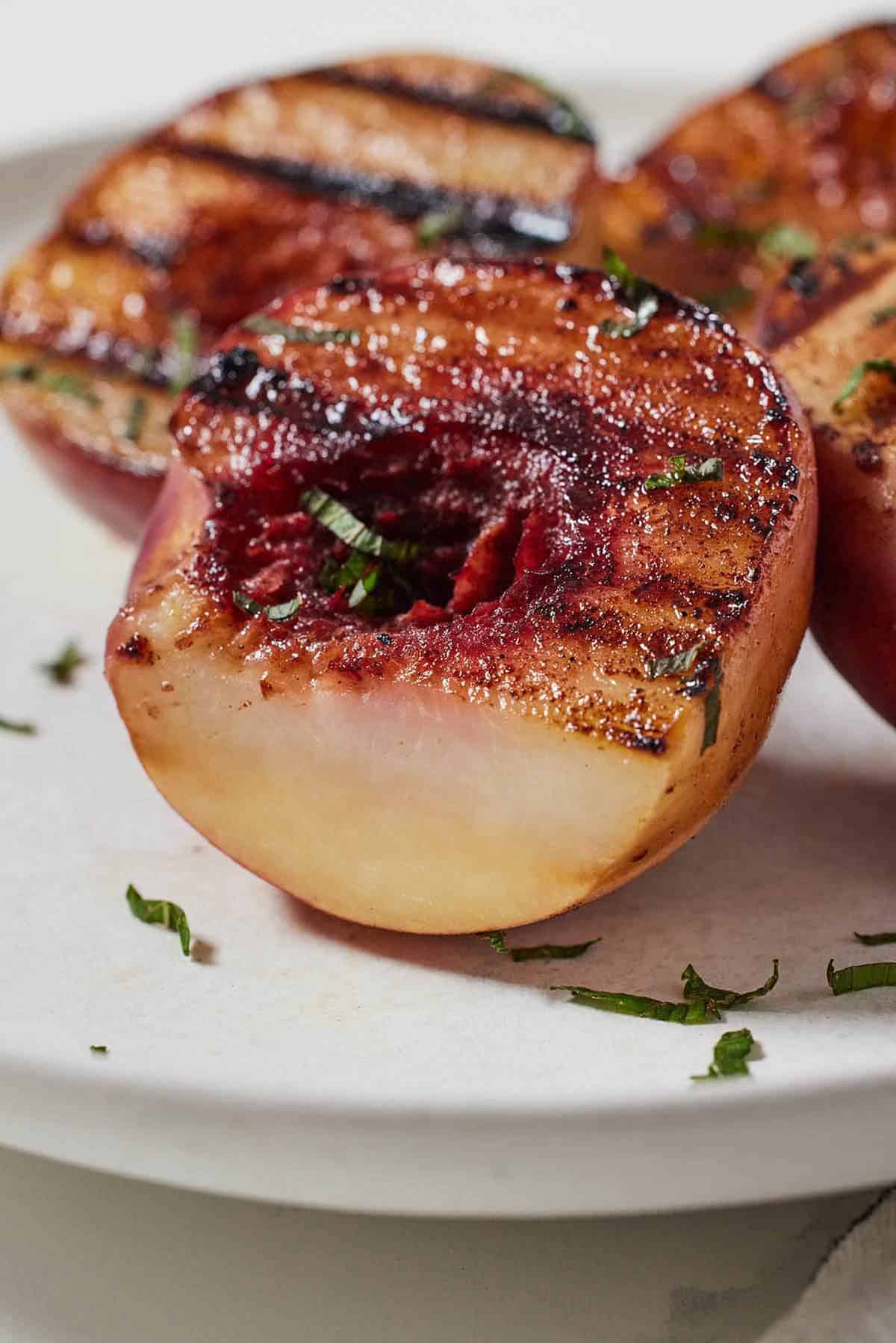 Close up of a grilled peach with a portion sliced off.