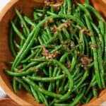 Pinterest graphic of an overhead view of a wooden bowl with crispy shallot green beans.