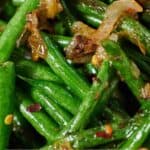 Pinterest graphic of a close view of crispy shallot green beans with red pepper flakes.