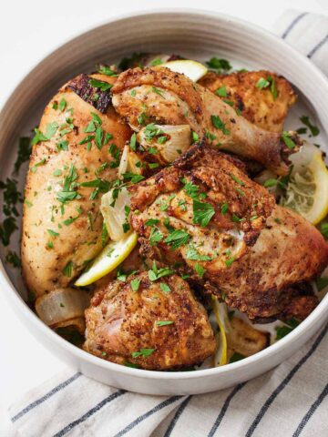 A white bowl of air fryer Lebanese chicken with fresh chopped herbs on top.