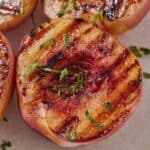 Pinterest graphic of a close view of one of four grilled peaches with mint scattered on top.
