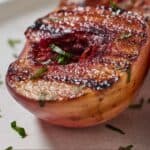 Pinterest graphic of a close view of a grilled peach with some chopped mint on top.