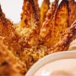 Pinterest graphic of a close up view of an air fryer blooming onion with a dip in front.