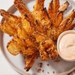 Pinterest graphic of an overhead view of an air fryer blooming onion on a plate with a small bowl of dip.