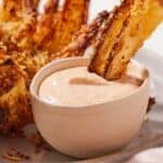 Pinterest graphic of a piece of air fryer blooming onion dipped into the dip.