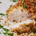 Pinterest graphic of a cut air fryer parmesan crusted chicken with chopped fresh parsley on top.