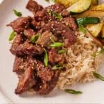Pinterest graphic of a serving of air fryer steak bites over some rice and zucchini.