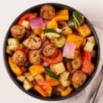 Overhead view of a bowl of air fryer sliced sausage, zucchini, onions, bell peppers, and potatoes.