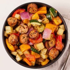 Overhead view of a bowl of air fryer sliced sausage, zucchini, onions, bell peppers, and potatoes.