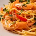 Pinterest graphic of a close view of shrimp over a plate of red curry pasta.